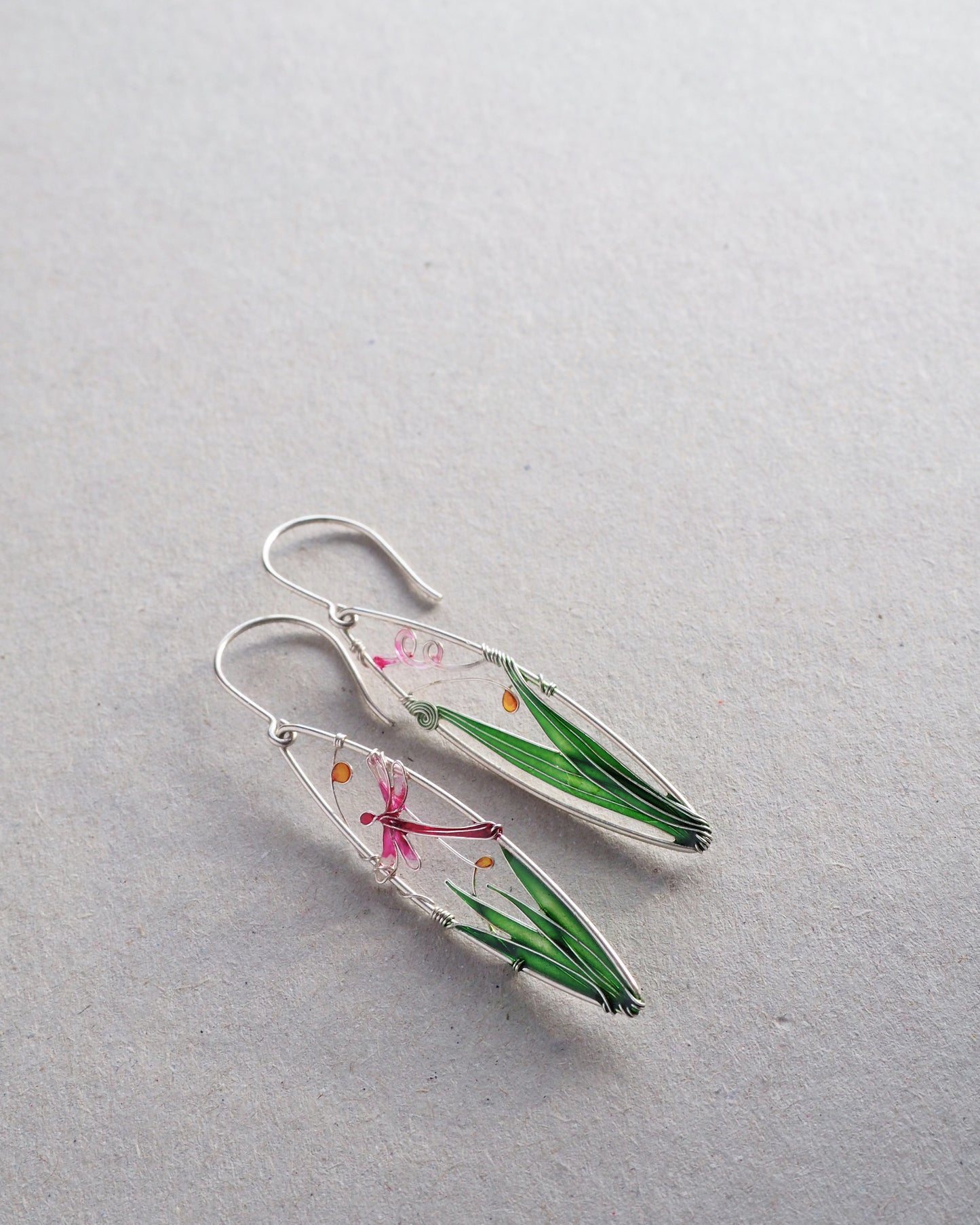 Earrings with floral and grass elements on a light gray background