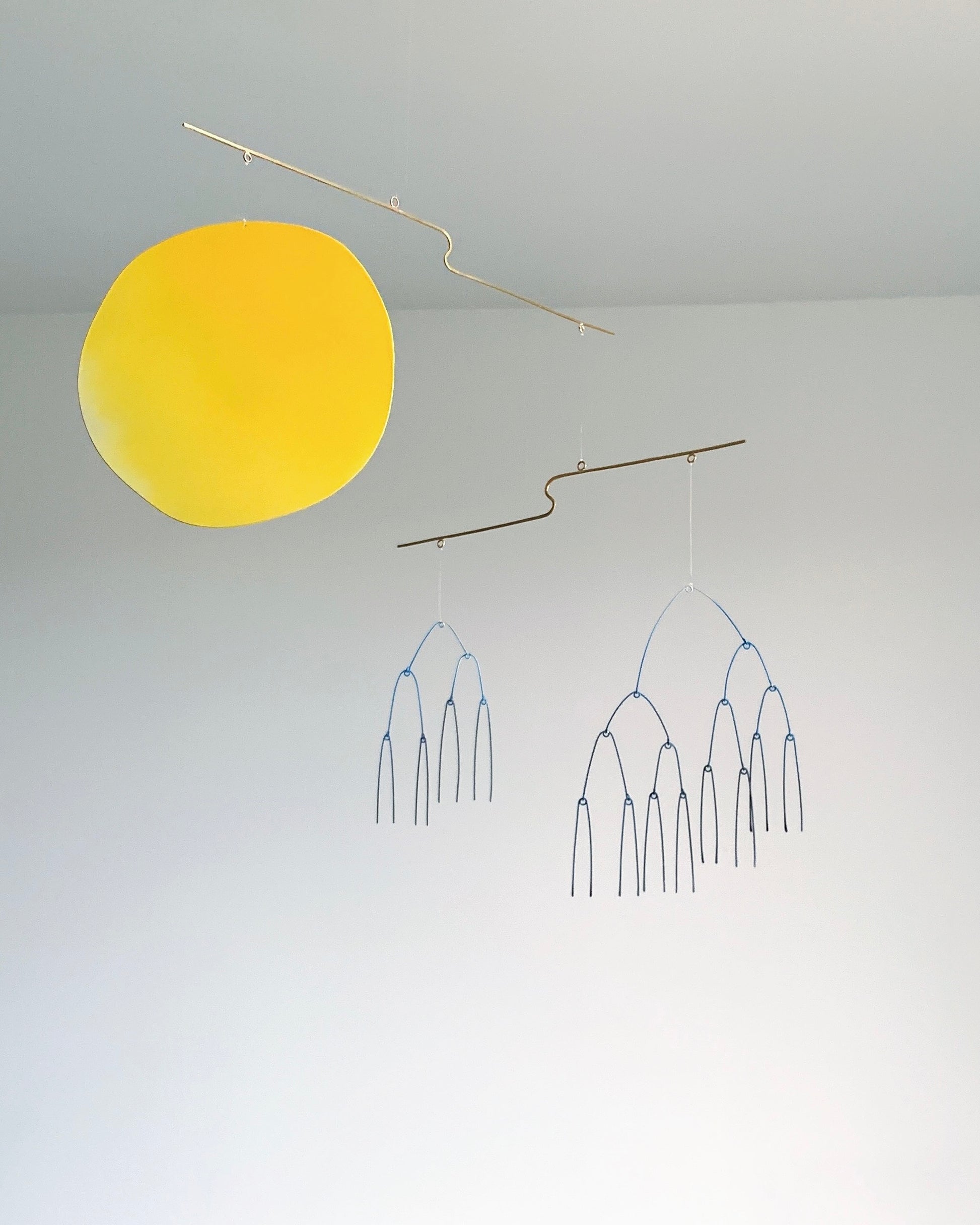 Yellow round object and branch-like sculpture on a gray background