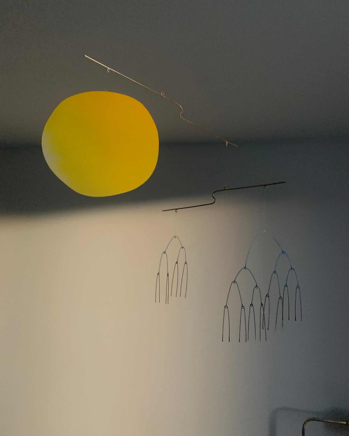 Hanging Sculpture with a yellow circular object hanging from the ceiling against a dark background
